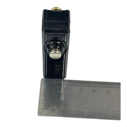 A small black plastic cylindrical component with a silver metal button or cap, shown upright next to a metal ruler on a plain white background.