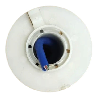 A top-down view of a white plastic circular component, likely a fuel cap or pump assembly, featuring a blue insulated cable or hose inserted into the center opening.