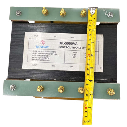 A 240V/120V control transformer with a black ribbed core, green metal end plates, and brass terminal screws, shown with a yellow tape measure indicating its dimensions.