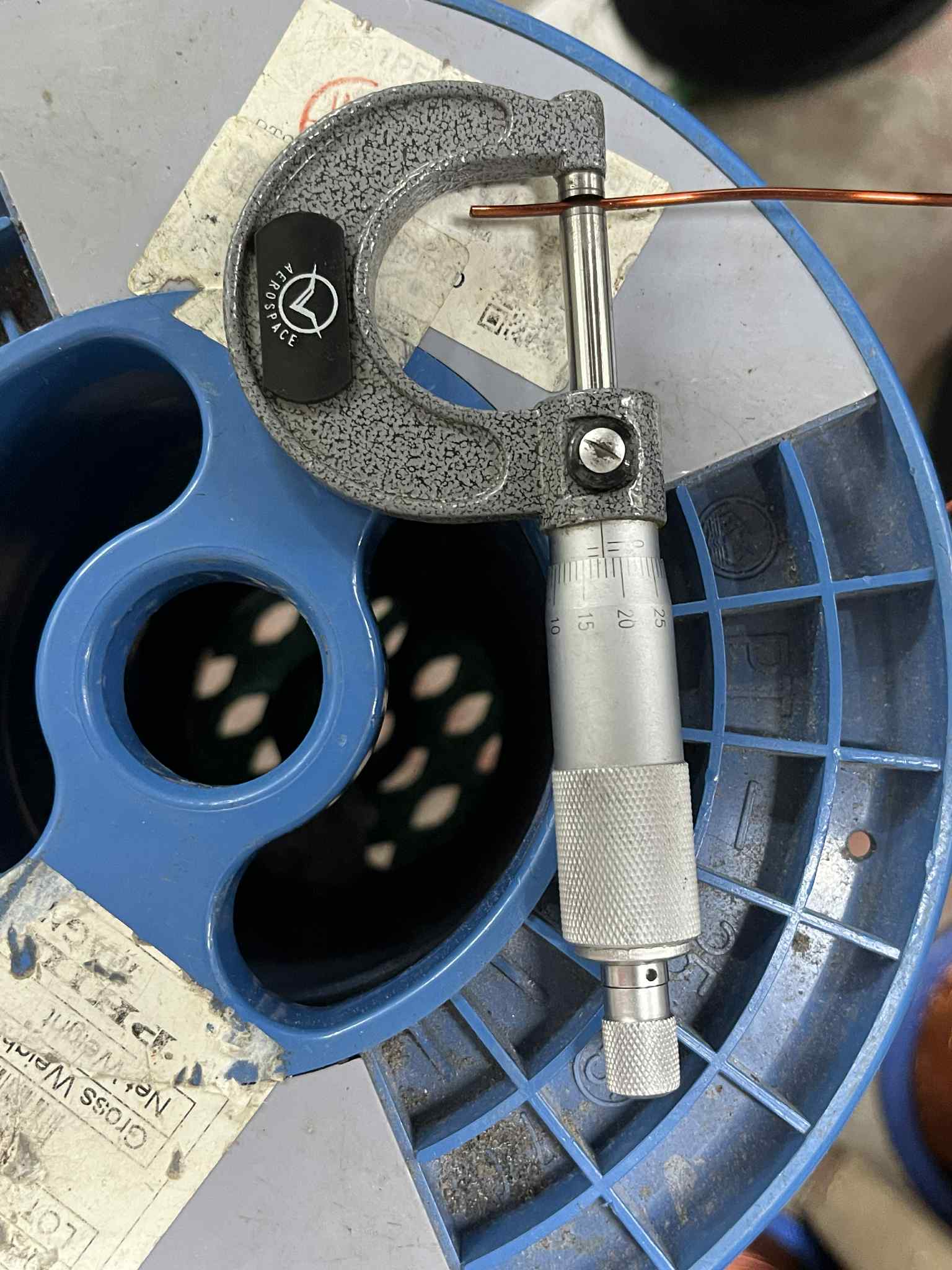 Measuring AWG 14 magnet wire with a micrometer tool on a blue wire spool
