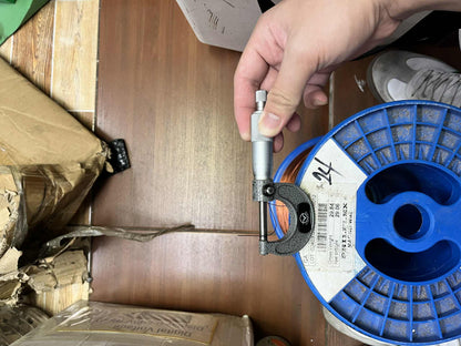 Philflex AWG 24 magnet wire 200 Grams spool held in hand with blue base and measuring tool
