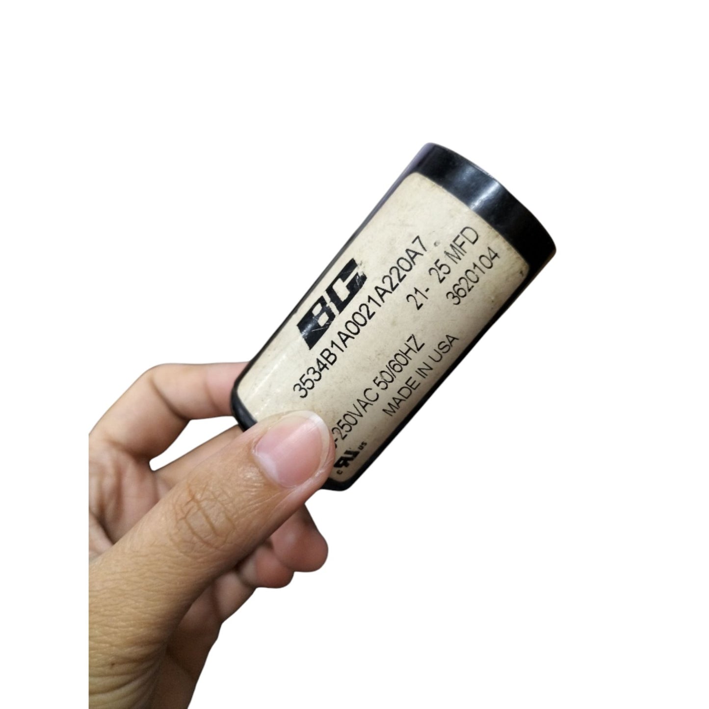 BC Motor Starting Capacitor 21-25uF 250V held in hand, ideal for electrical applications.
