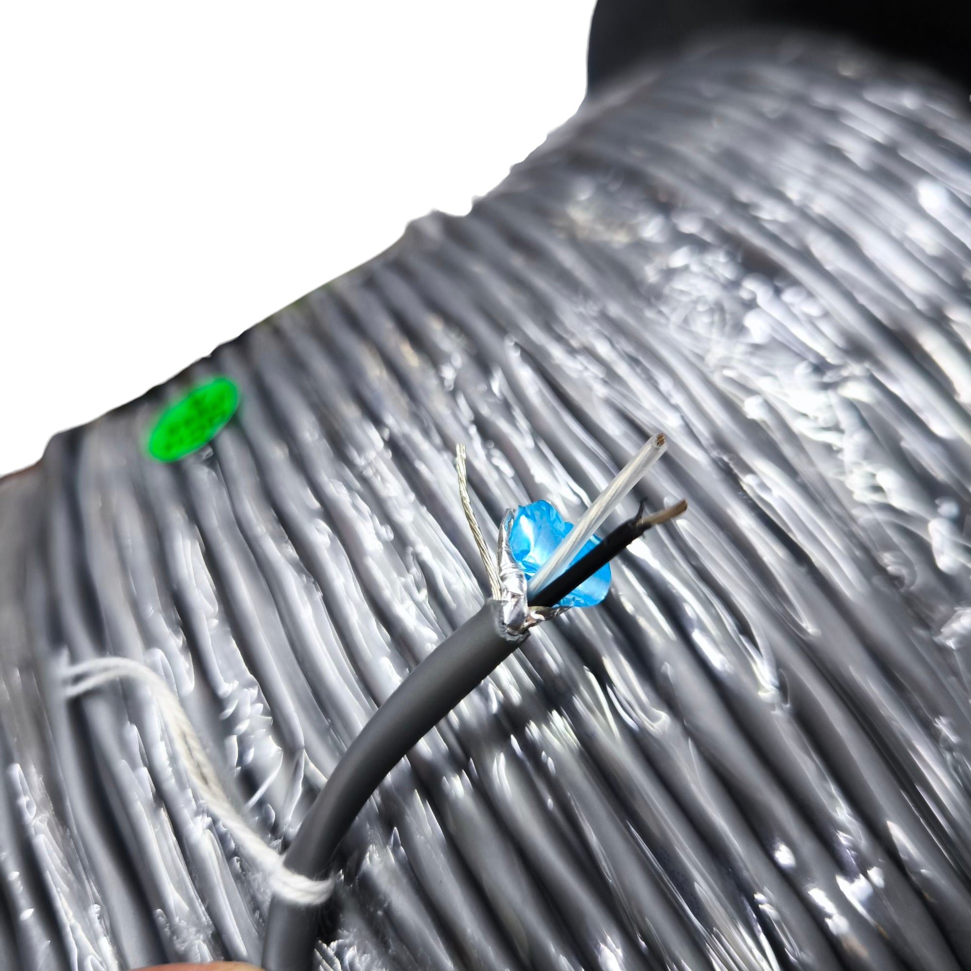 Close-up of Belden 22AWG shielded cable showing black and white wires with foil shielding on a large roll