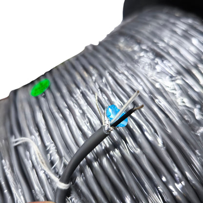 Close-up of Belden 22AWG shielded cable showing black and white wires with foil shielding on a large roll