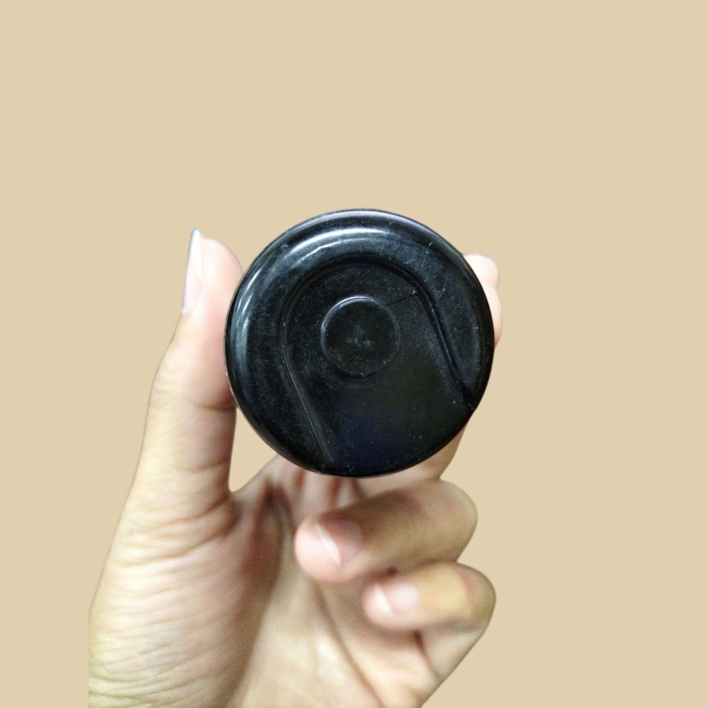 Close-up of a hand holding a 200-240MFD motor start capacitor in black with a smooth finish