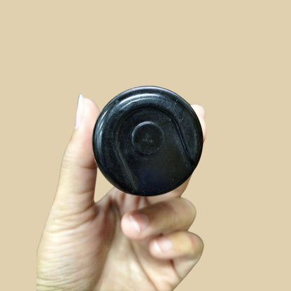 Close-up of a hand holding a 200-240MFD motor start capacitor in black with a smooth finish