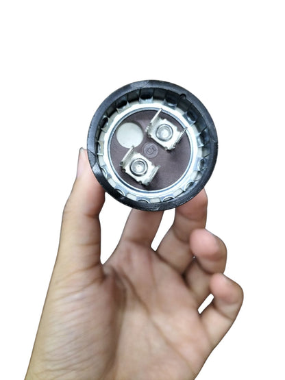 88-106MFD 250V AC capacitor held in hand, showcasing its terminal connections and round design