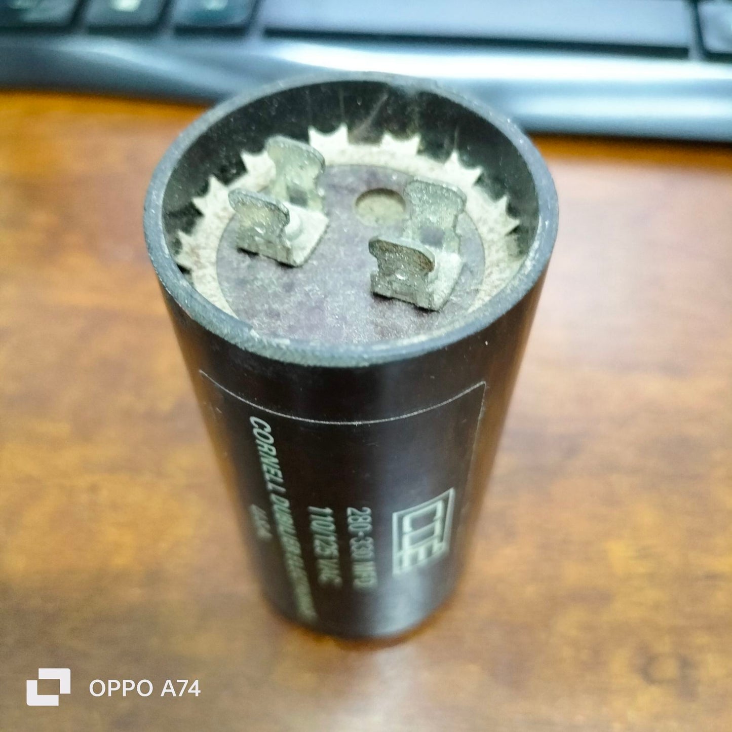 Brand CDE 280-330 MFD 110-125V electrical capacitor with metal terminals on wooden surface