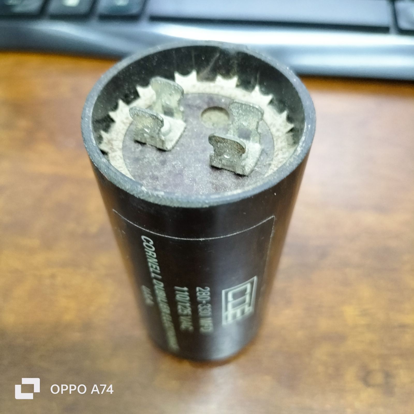 Brand CDE 280-330 MFD 110-125V electrical capacitor with metal terminals on wooden surface