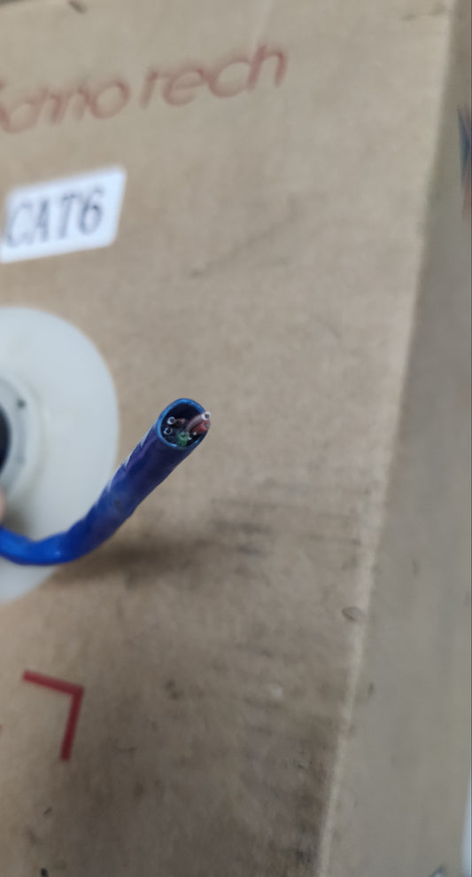 Close-up of AMP CAT6 LAN cable 100 meters blue networking cable with exposed wires on cardboard box