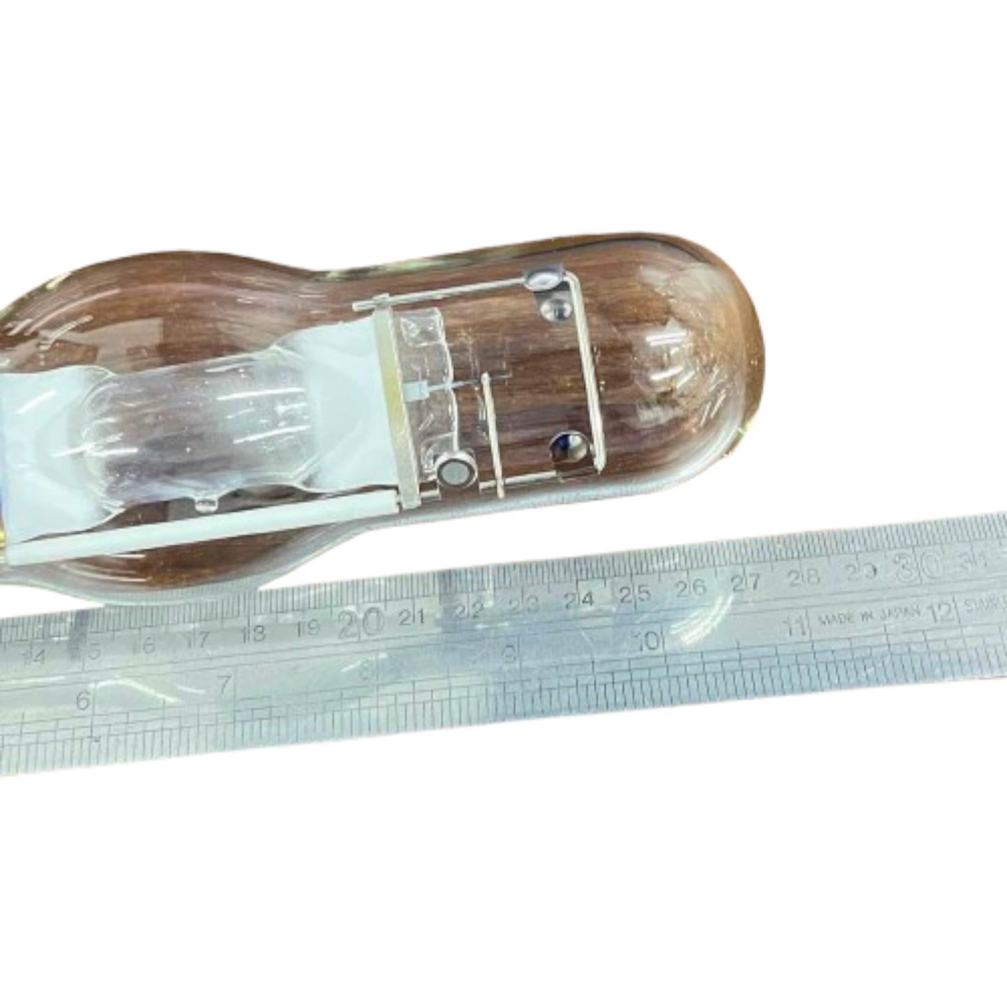 Glass light bulb with wooden casing next to a ruler on a white background