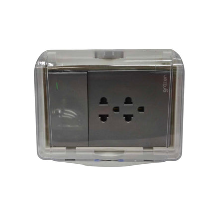 A wall outlet covered in a clear plastic protective case, shown against a plain white background. The outlet has two three-pin UK plugs, and the brand name 'grzeten' is printed vertically on the right side.