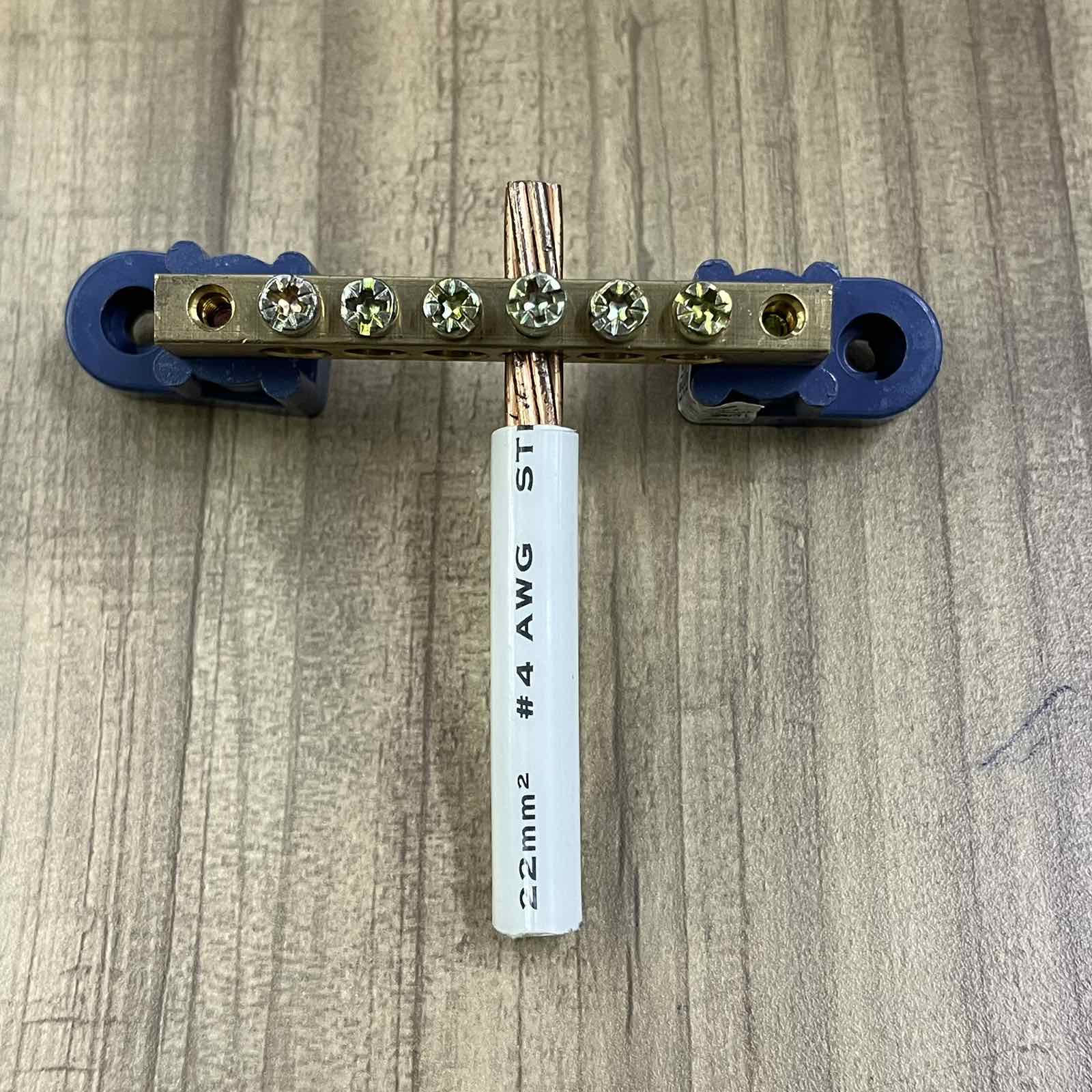 Grippes Grounding Bus Bars 4 Holes with copper wire and blue mounting brackets on wood surface
