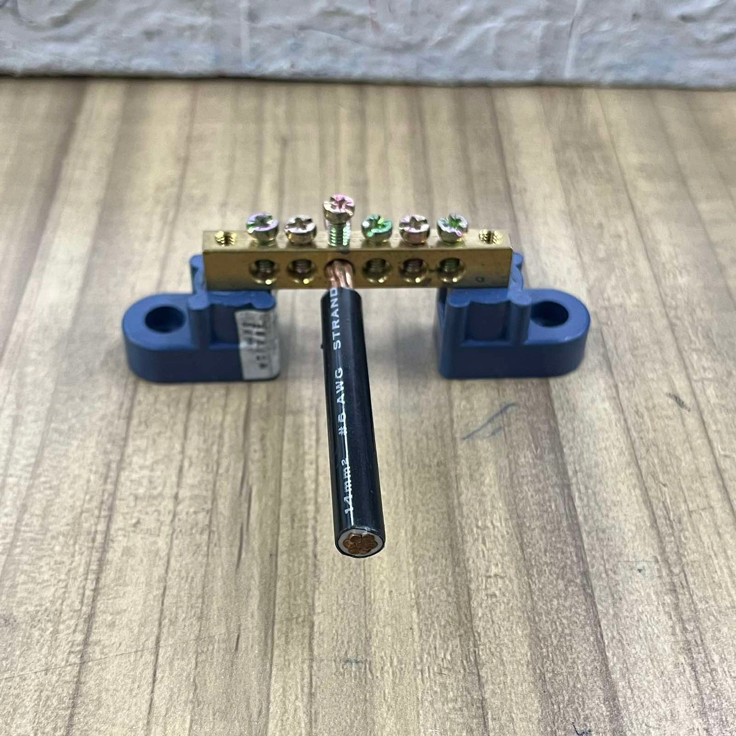 Grippes Grounding Bus Bars 4 Holes mounted with black electrical wire on wooden surface