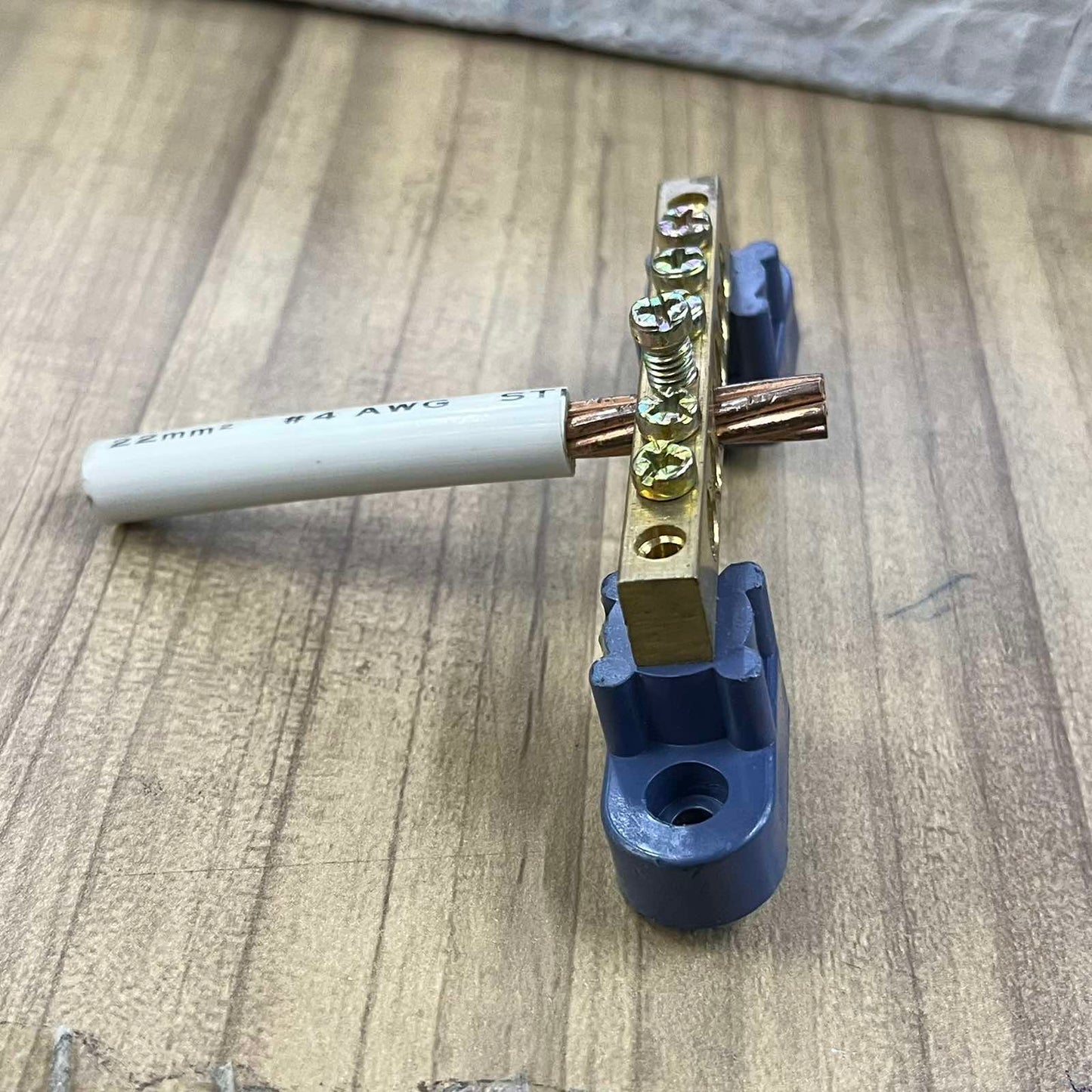 Grippes Grounding Bus Bars 4 Holes with attached copper wire and mounting brackets on wooden surface