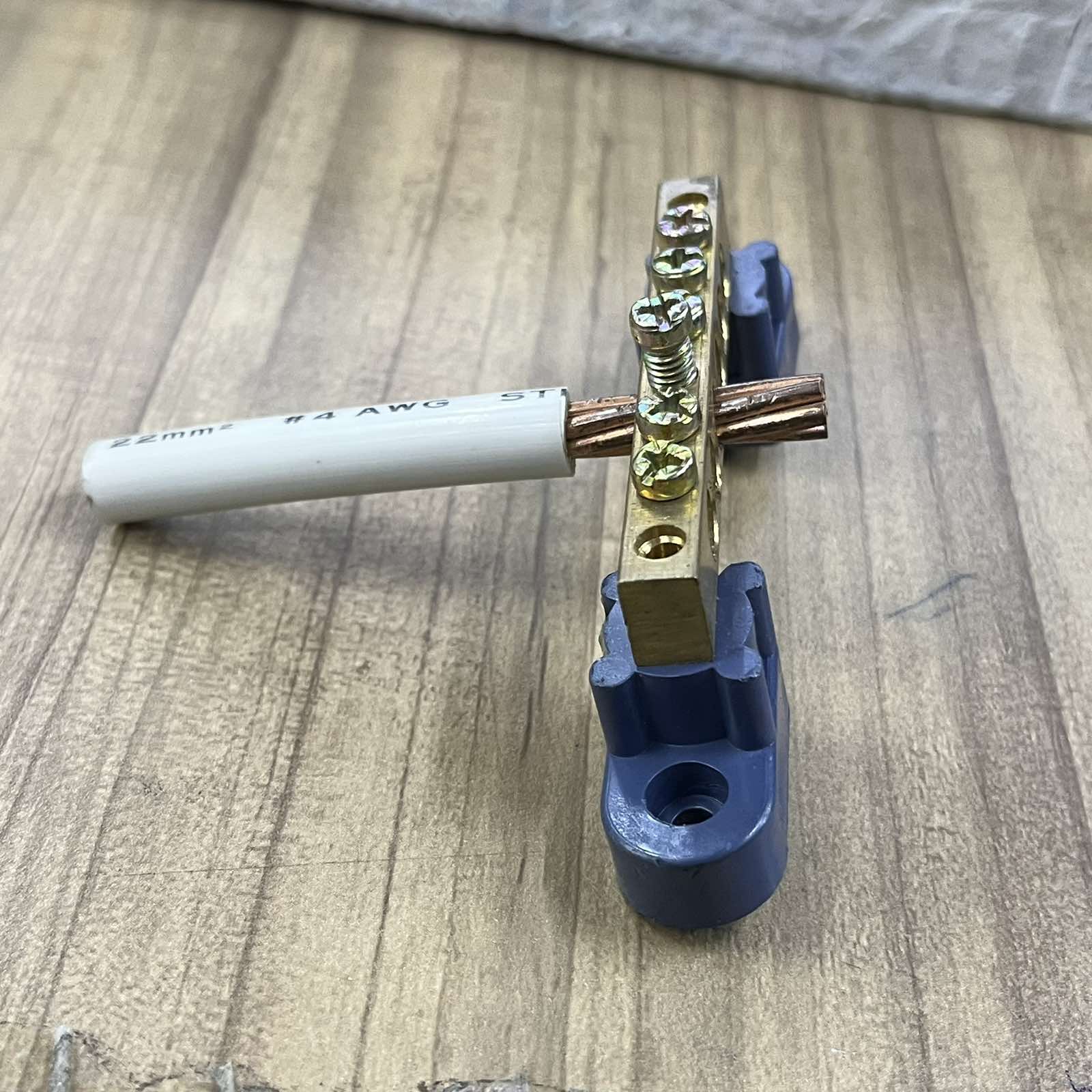 Grippes Grounding Bus Bars 4 Holes with attached copper wire and mounting brackets on wooden surface