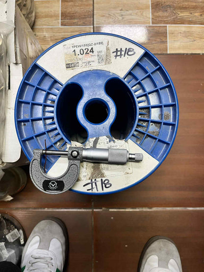 Blue spool of Magnet Wire AWG 18 100 Grams on a wooden floor with measurement tool