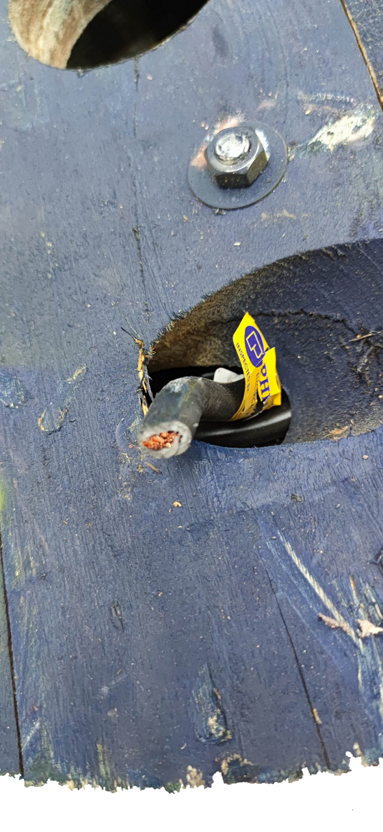 Cut end of black Philflex 30mm welding cable with exposed copper strands and yellow vendor tag on wooden spool