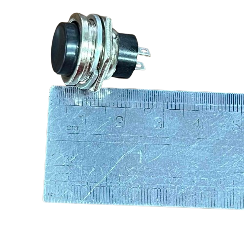 Push Button 1A 220V Black positioned next to a ruler for size reference