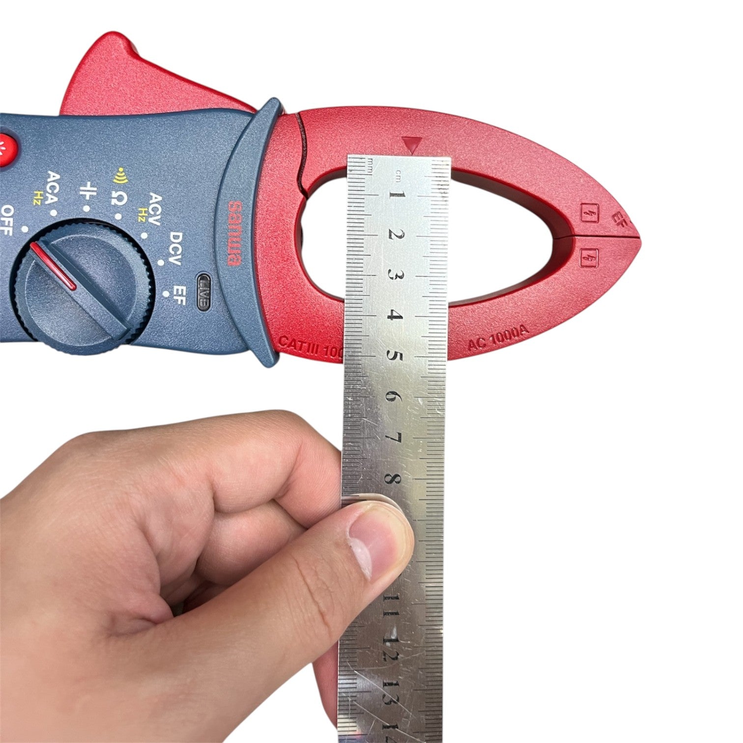 Hand holding a metal ruler next to a red and blue tool on a white background Sanwa Digital AC Clamp Meter DCM301 Measure True RMS Method ACA 60A/600A/1000A Made In Japan Electx Electrical SUpply