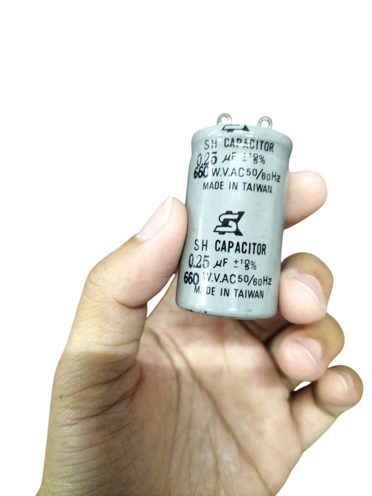 SH running capacitor for Motor with specifications on metal casing and hand holding the capacitor