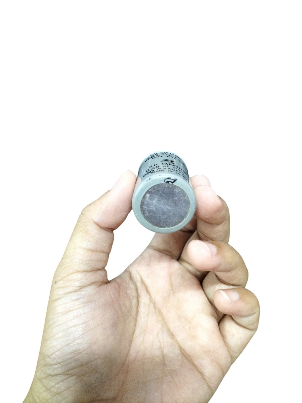 Hand holding an SH running capacitor for Motor, designed for electrical efficiency and performance