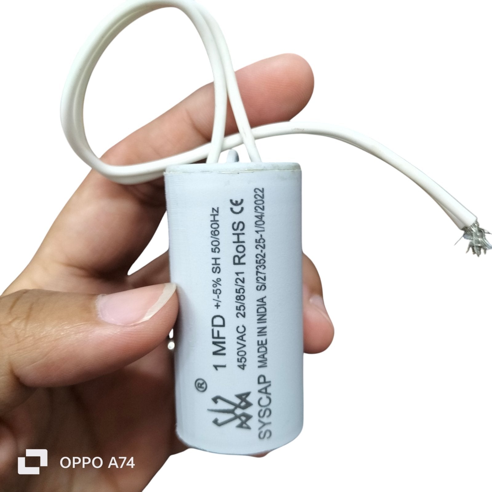 Syscap 1MFD 450V AC Running Capacitor electrical component held in hand with white wires