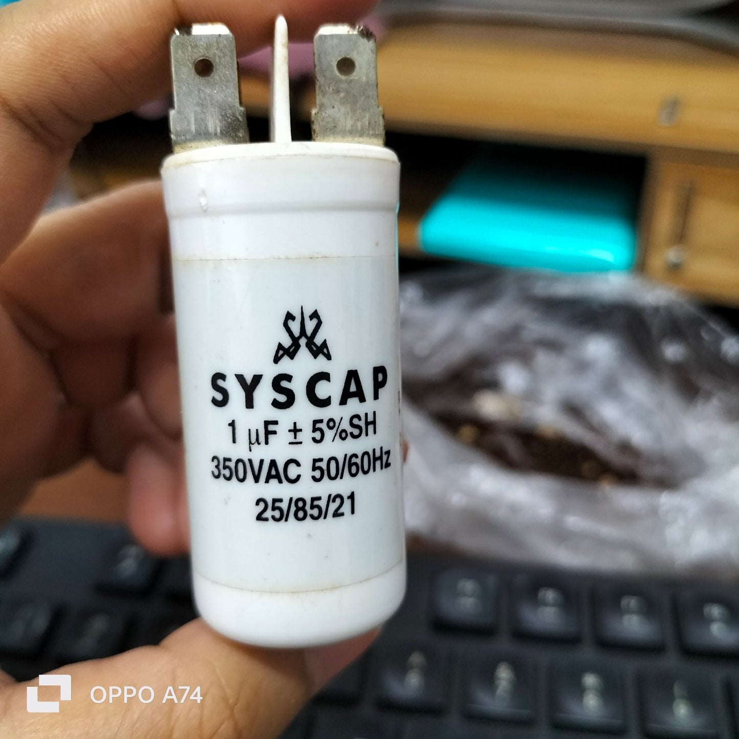 Syscap 1UF 350V AC Running Capacitor electrical component held in hand with clear labeling