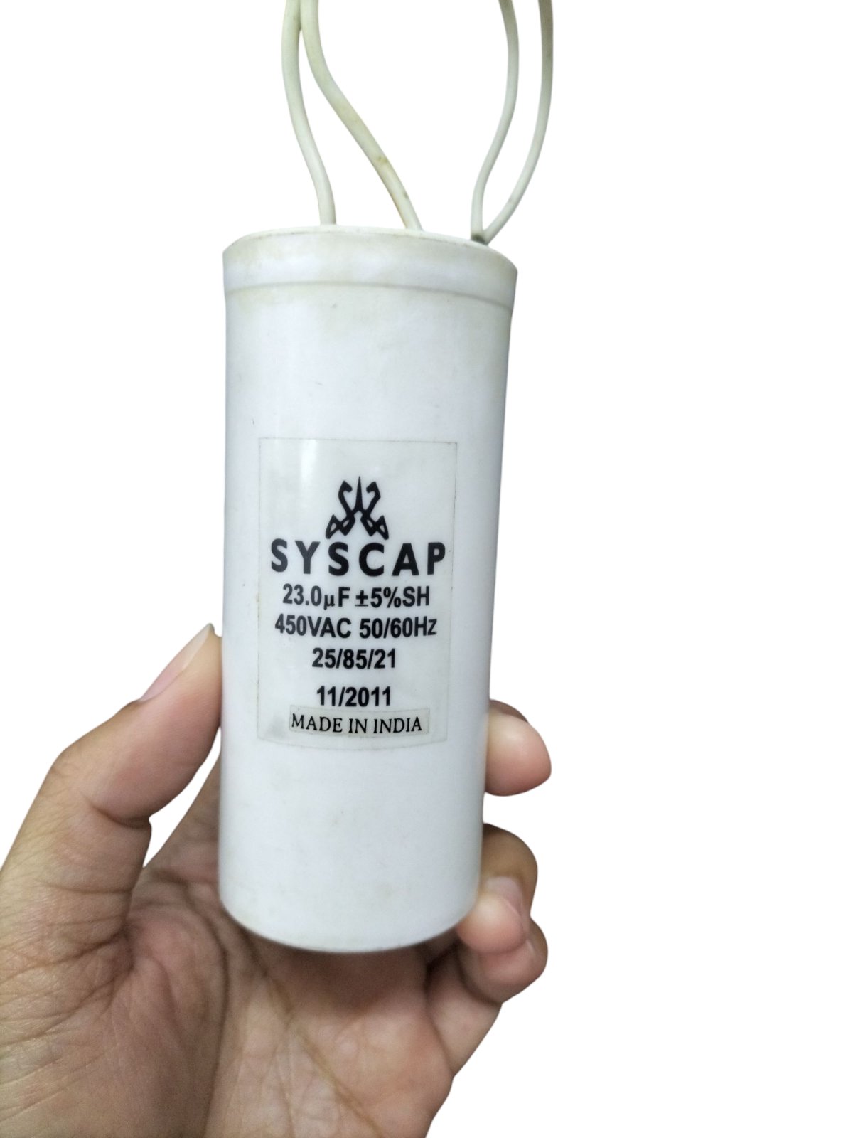 Syscap 23MFD 450VAC motor capacitor white cylindrical electrical component held in hand