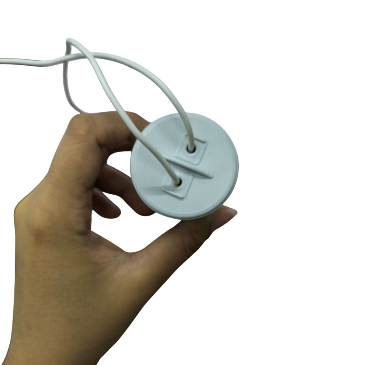 Hand holding Syscap electrical capacitor for motors with connected white wires isolated on white