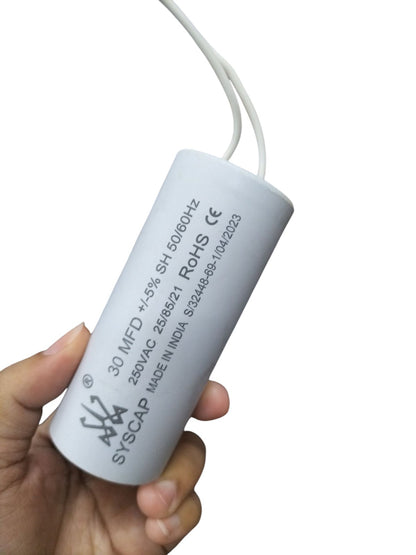 Hand holding Syscap industrial motor capacitors white cylindrical electrical component with wires