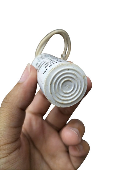 Hand holding a Syscap Motor Capacitor 250V AC displaying the connector and specifications on the body