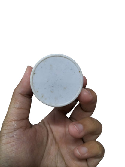 Syscap Motor Capacitor held in hand, featuring a round and flat design for electrical circuit applications.