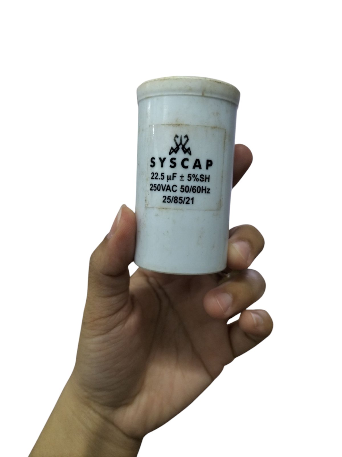 Syscap motor capacitor for industrial use held in hand with specifications visible