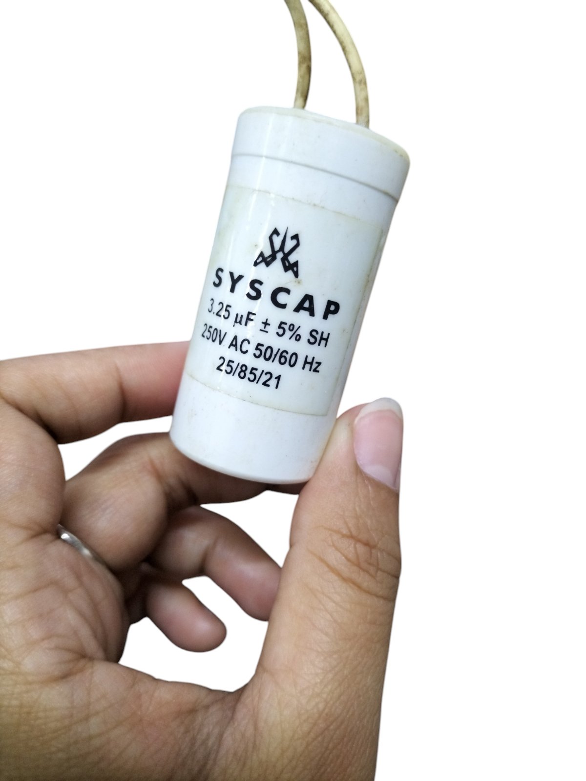 Syscap motor capacitor 3.25 uF 250V AC electrical circuitry part held in hand