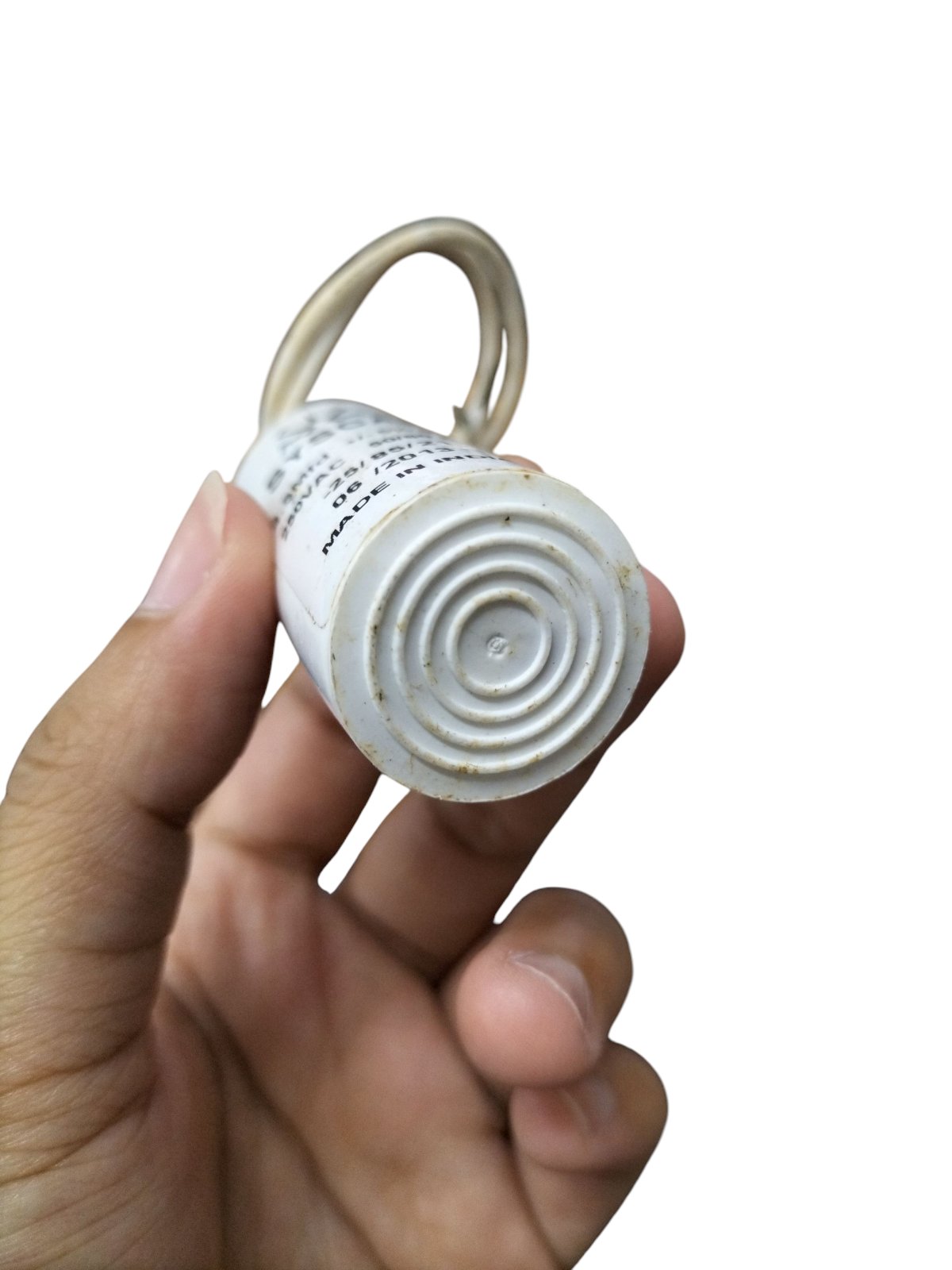 Hand holding a Syscap Motor Running Capacitor 250V AC showcasing its bottom design and wire connection