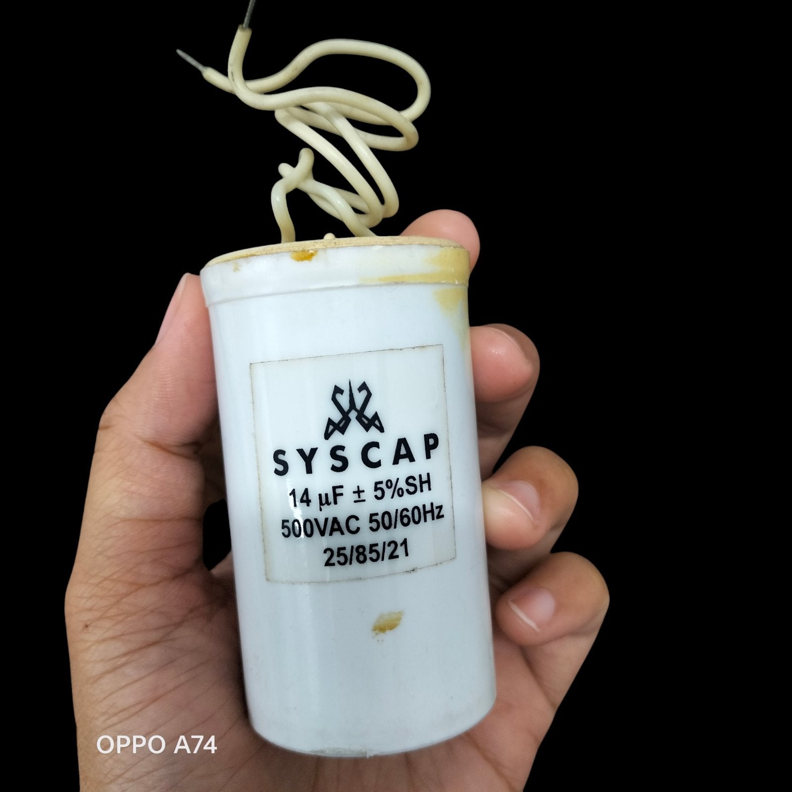 Syscap Run Capacitor 14UF 500 VAC electrical component with wires held in hand for circuitry use