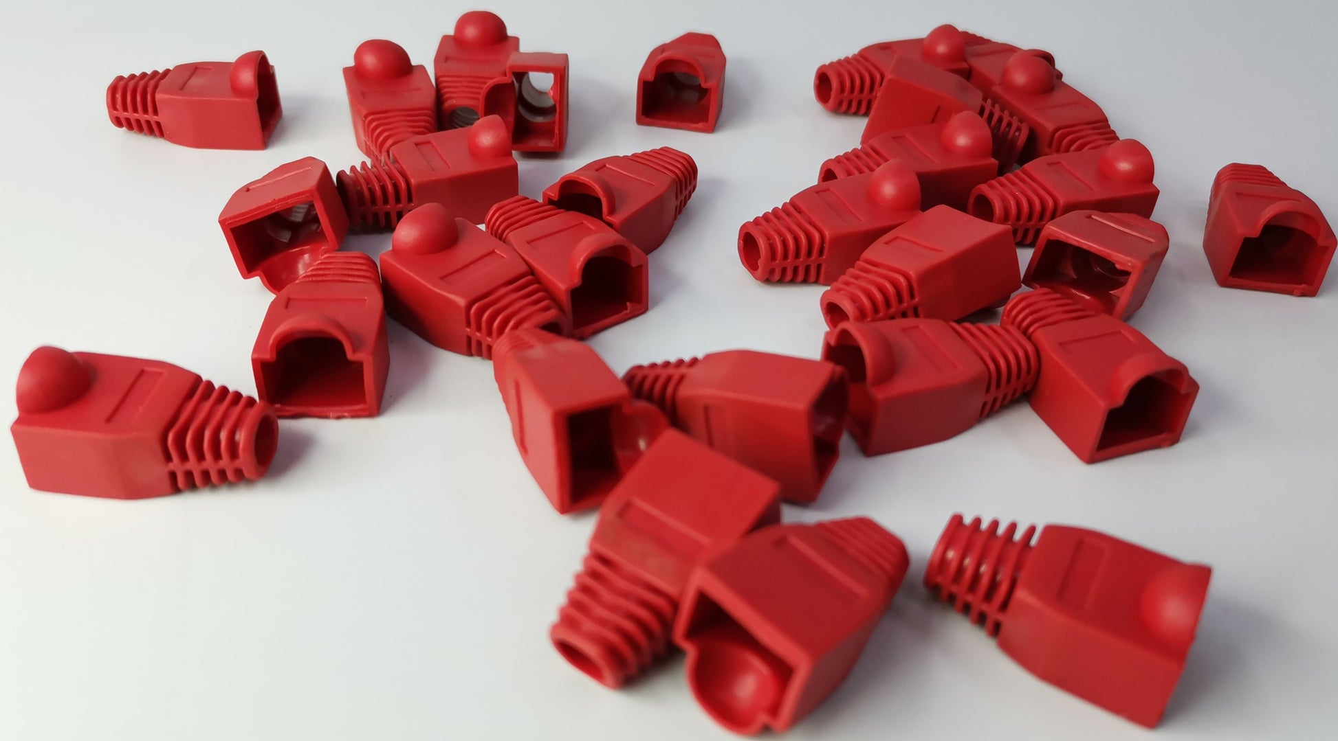 Red Rubber BooT RJ45 Grippes protective covers for Ethernet cables by Grippes scattered on white surface